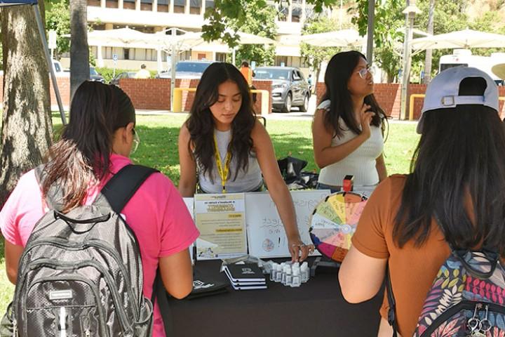 Staff speaking with students gathered at a tabling events.